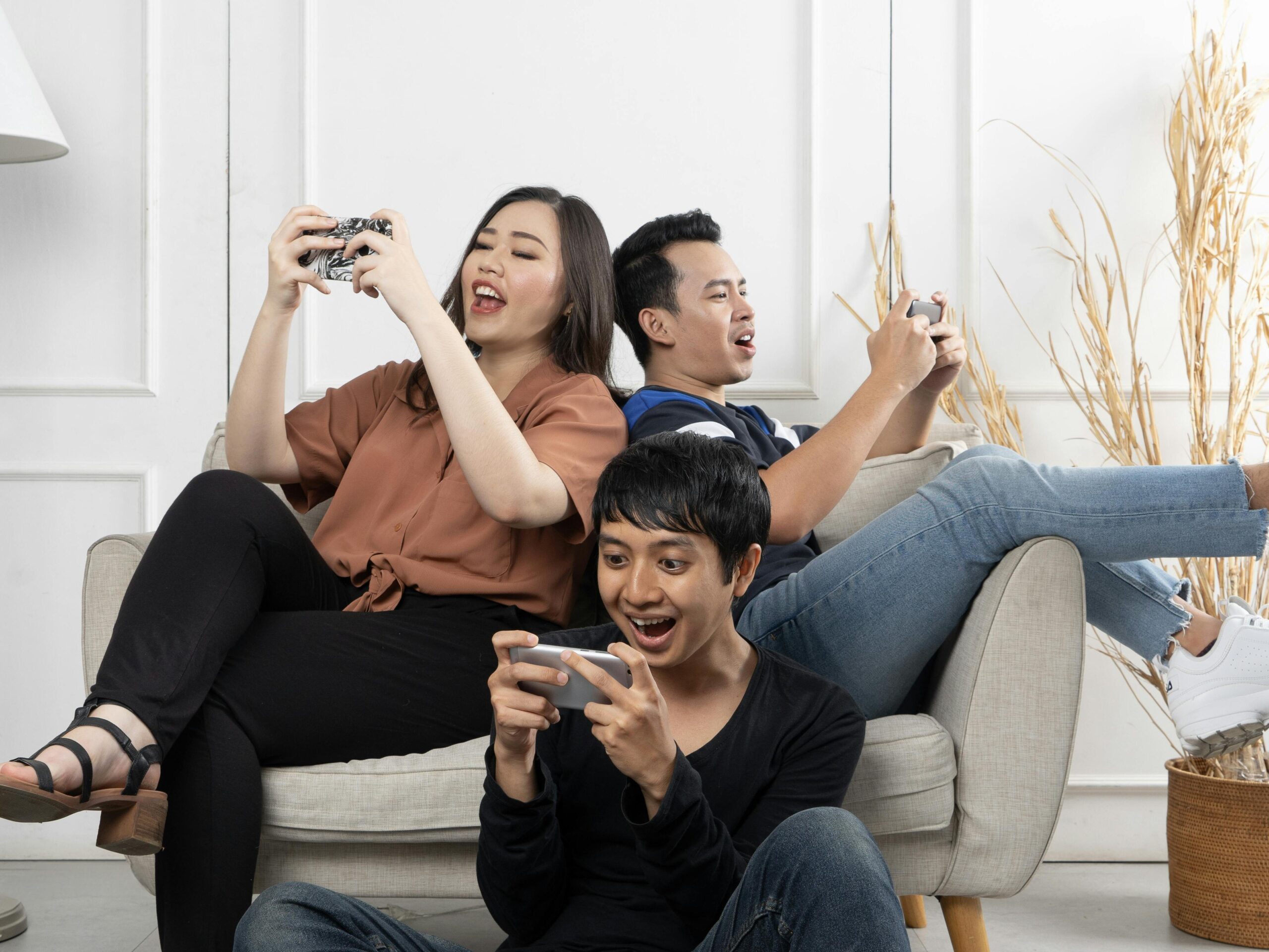 Three friends enthusiastically playing video games indoors, having fun and relaxing.