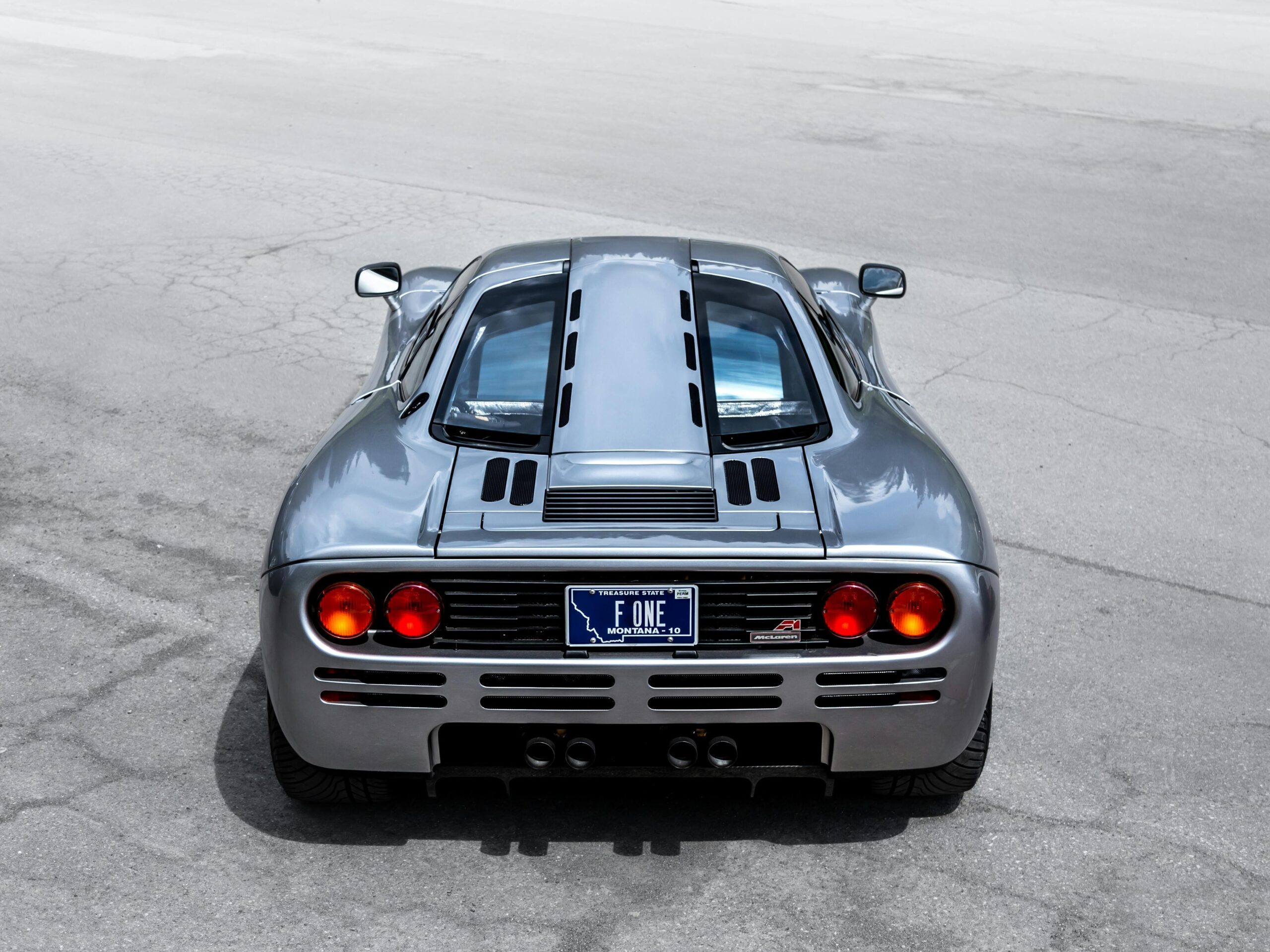 A sleek McLaren supercar captured from the rear on an open road, highlighting its design and elegance.